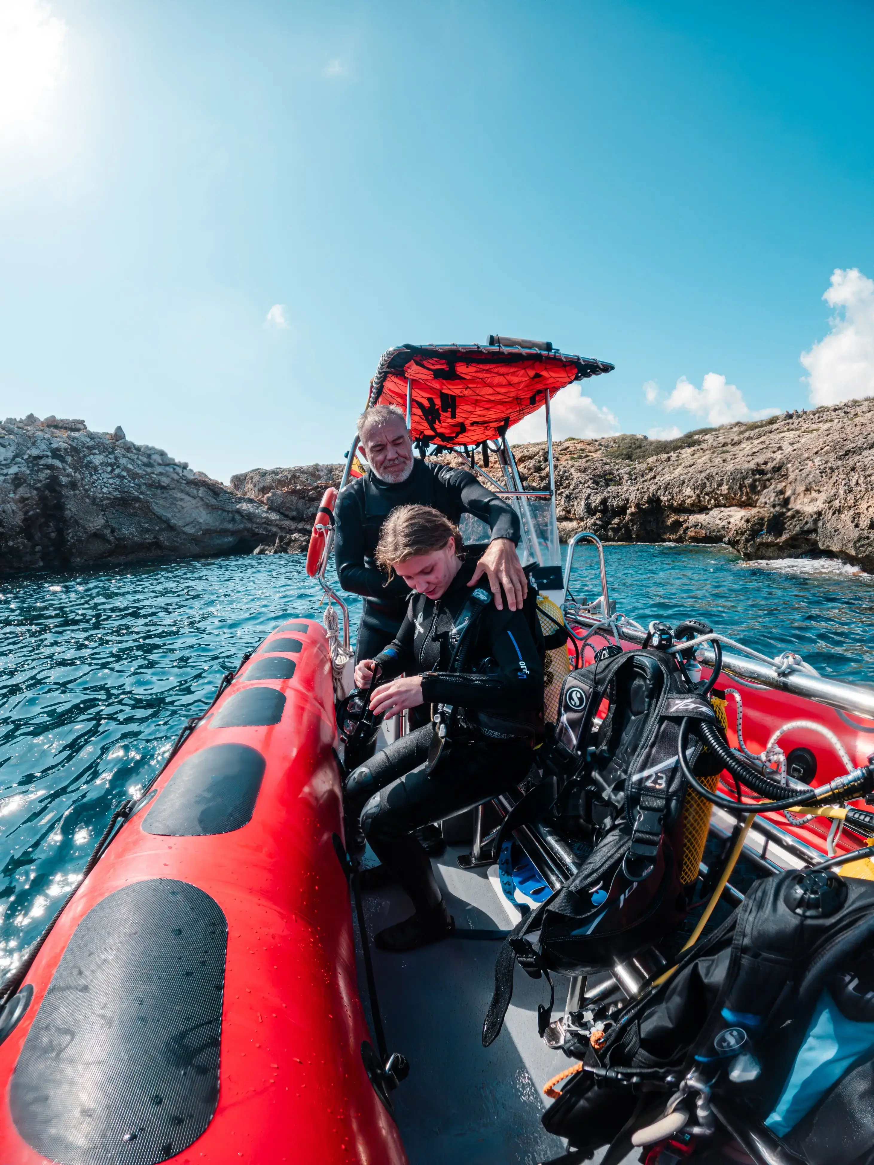 Dive instructor helping a student prepare on a dive boat off the Mallorca coast